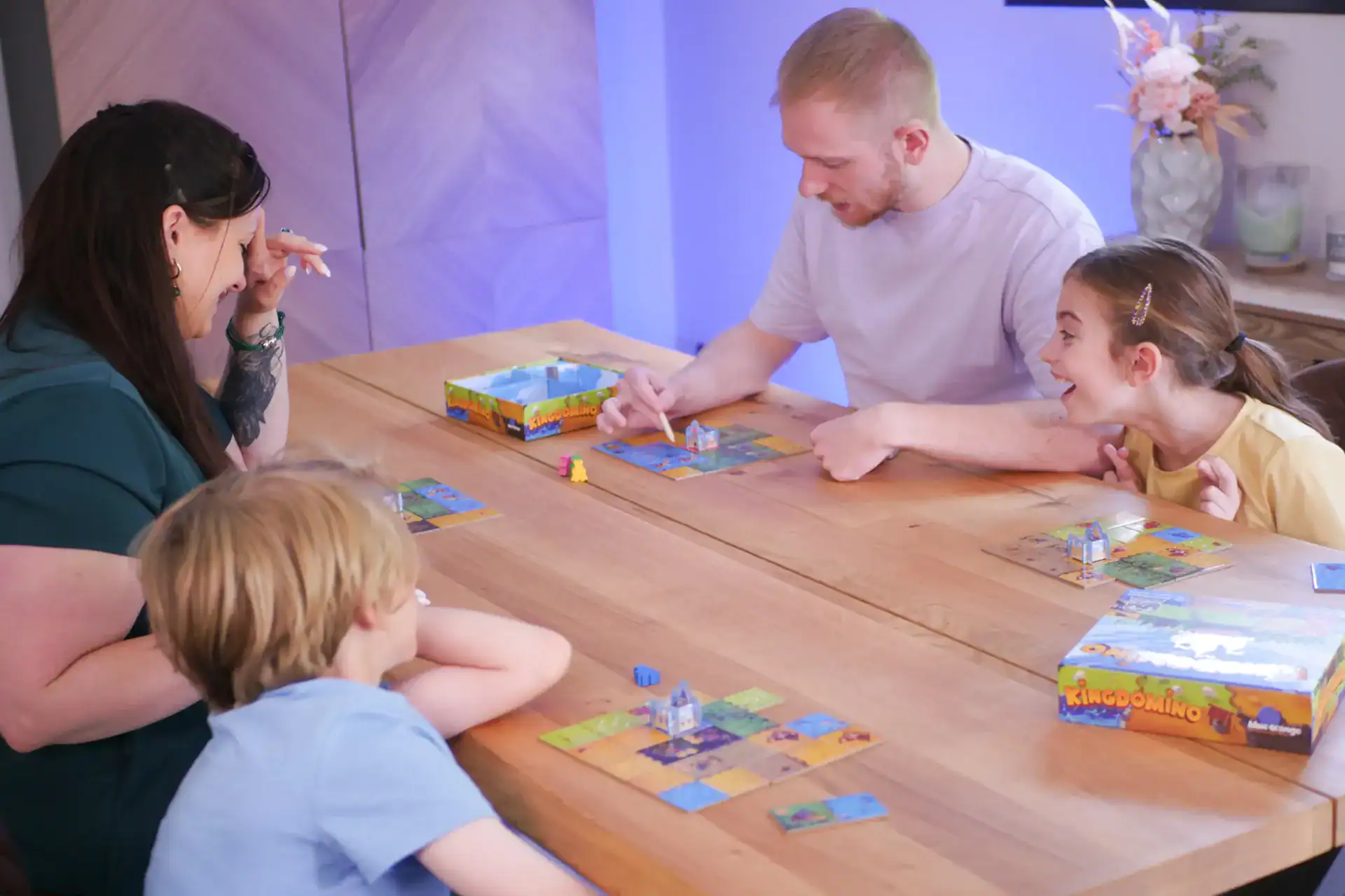Familie spielt gemeinsam Brettspiel am Tisch im Brettspielcafé.